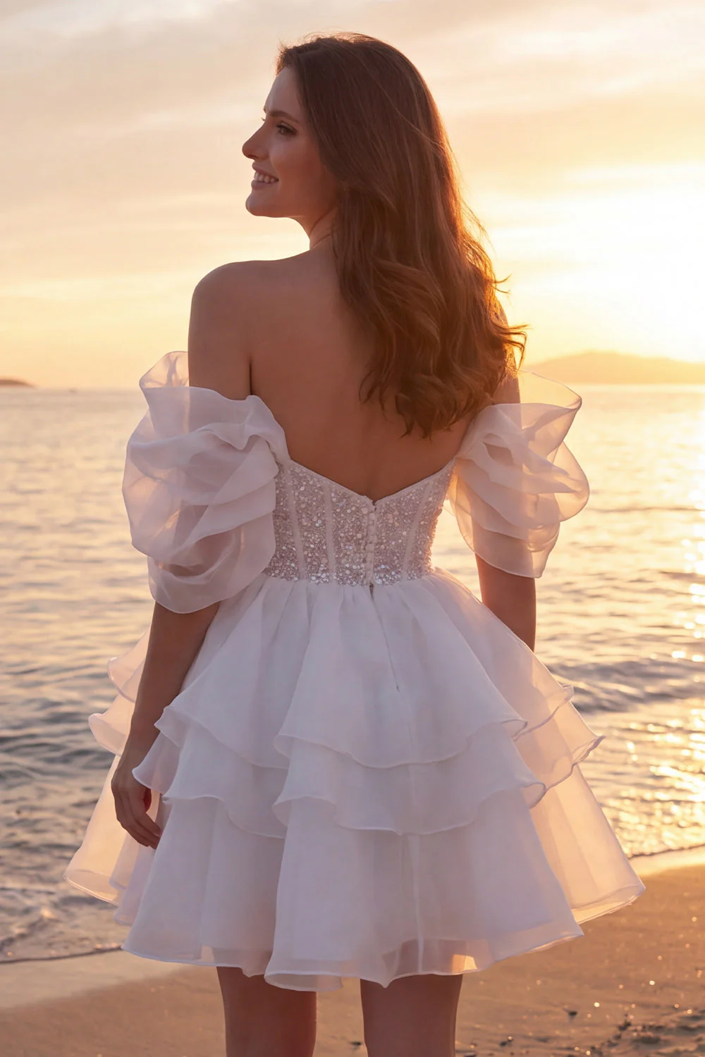 Une robe de mariée courte et pailletée en ivoire avec des volants - Image 2