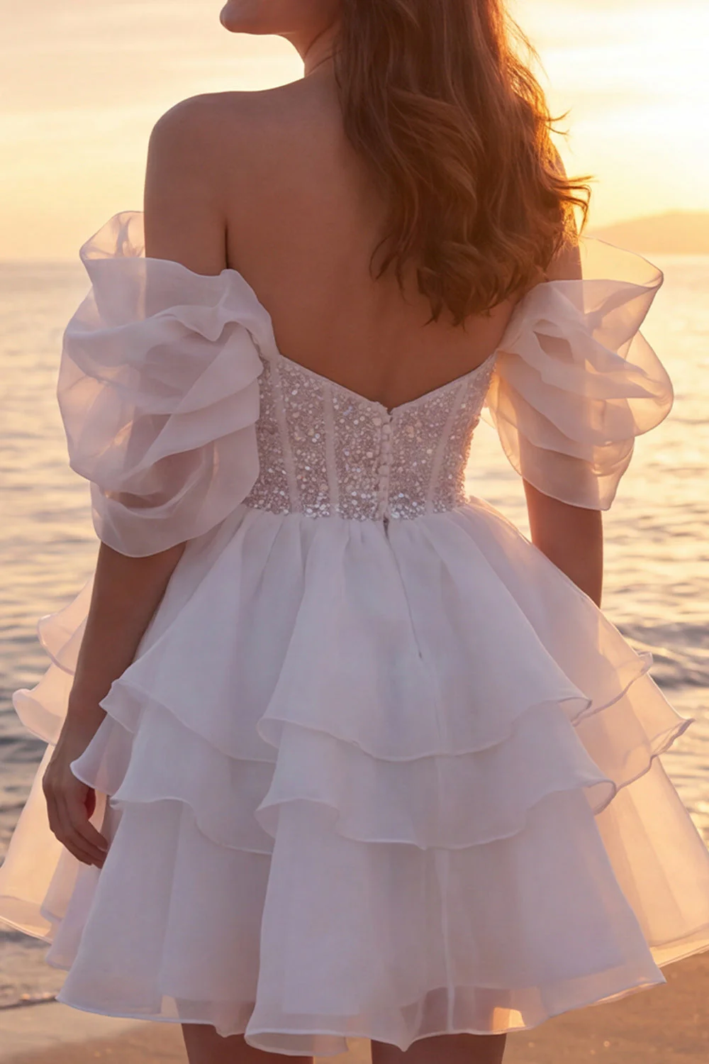 Une robe de mariée courte et pailletée en ivoire avec des volants - Image 4